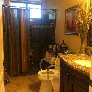 A neatly organized bathroom with a shower curtain, toilet, and sink adorned with decorative elements.