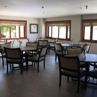 An empty dining room with several tables and chairs near large windows.