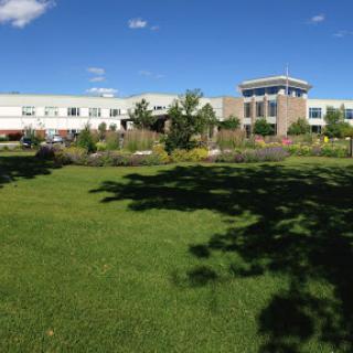 A modern building surrounded by lush greenery under a clear blue sky.