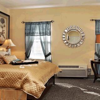 A cozy bedroom with elegant decor, featuring a large bed, stylish mirror, and soft lighting.