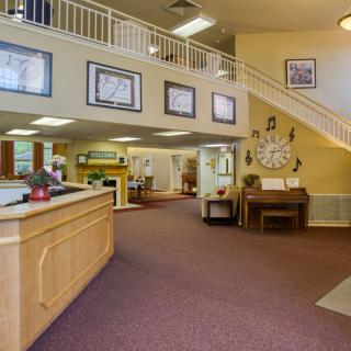 A spacious reception area featuring a wooden desk, staircase, and decorative elements on the walls.