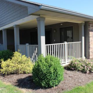A well-maintained porch with greenery and a white fence.