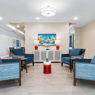 A modern waiting room with blue chairs and a colorful painting on the wall.