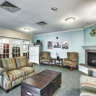 A cozy living room with comfortable seating, a fireplace, and decorative art on the walls.