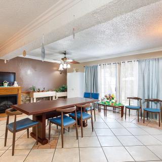 A spacious dining room featuring a large table with blue chairs, a fireplace, and large windows with curtains.