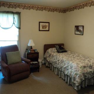 A cozy bedroom featuring a single bed and an armchair by the window