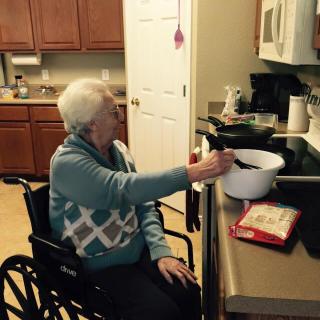 An elderly person in a wheelchair cooking in the kitchen, emphasizing accessibility and independence.