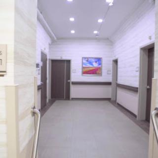 A modern hospital corridor featuring bright lighting and an artwork on the wall.