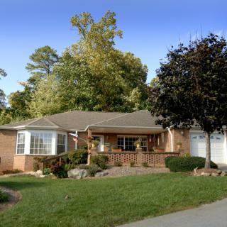 A cozy suburban house with a well-maintained yard and surrounding trees.