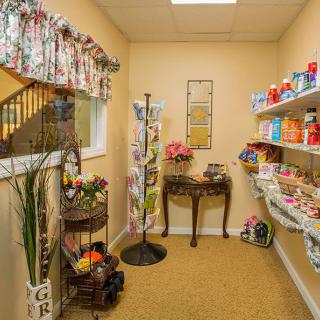 A cozy snack room with shelves stocked full of snacks, decorative plants, and a small table.