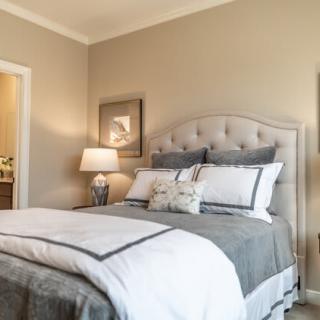 A cozy bedroom with a neatly made bed, stylish decor, and soft lighting.