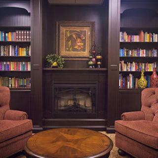 A cozy reading nook featuring bookshelves, armchairs, and a fireplace.