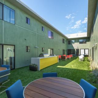 A modern courtyard with patio furniture between two residential buildings.