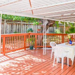A spacious wooden deck with a table and chairs under a covered area, surrounded by a railing.