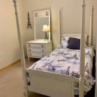 A cozy bedroom with a four-poster bed and matching dresser.