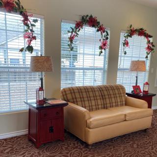 A cozy living room with a sofa, side tables, and floral decorations on the windows.