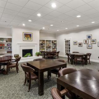 A spacious library reading room with tables, chairs, bookshelves, and a fireplace.
