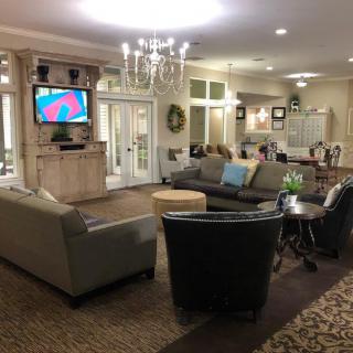 A cozy living room with sofas, chairs, a television, and a chandelier.