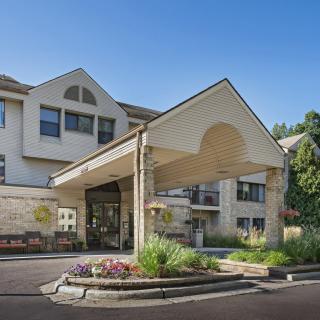 An exterior view of a building entrance with landscaping and clear blue sky.
