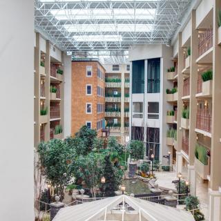 A spacious atrium with natural light, featuring an indoor garden and modern architecture.