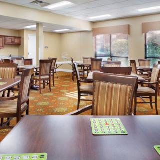 A spacious dining area with neatly arranged tables and chairs, complemented by large windows.