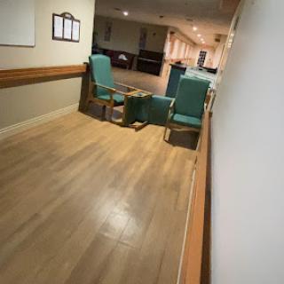 A quiet hallway featuring green chairs in a waiting area.