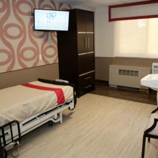 A modern hospital room with a bed, television, and medical equipment.