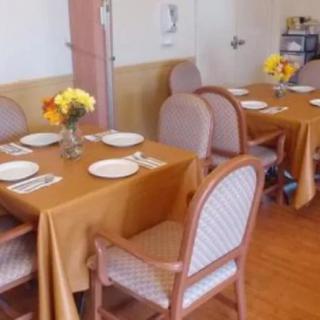 A neatly arranged dining area with tables set for guests, featuring floral centerpieces.