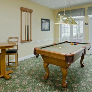 A cozy game room featuring a pool table, stylish lighting, and comfortable seating.