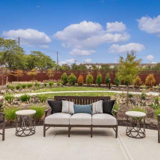 A beautifully landscaped garden with patio seating and clear blue skies.