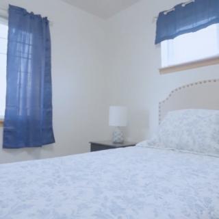 A simple bedroom with blue curtains and a neatly made bed.