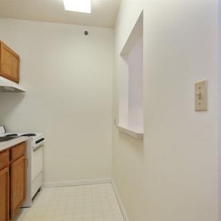 A small kitchen with wooden cabinets, a stove, and white walls.