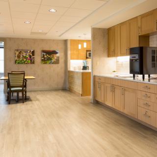 A modern kitchen with wooden cabinets and a small seating area adorned with decorative art on the walls.