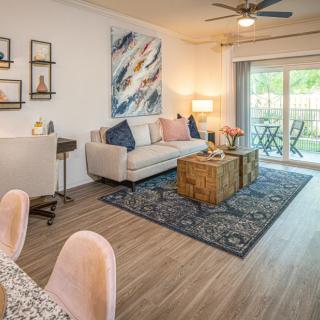 A stylish living room with modern decor, featuring a comfortable sofa, artistic wall decor, and access to a balcony.