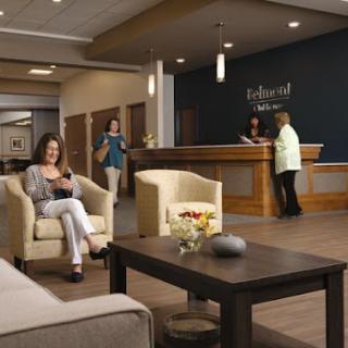 A modern lobby featuring comfortable seating, a reception desk, and people interacting.