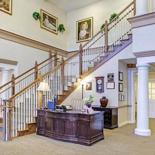 A spacious lobby with a grand staircase and a reception desk.