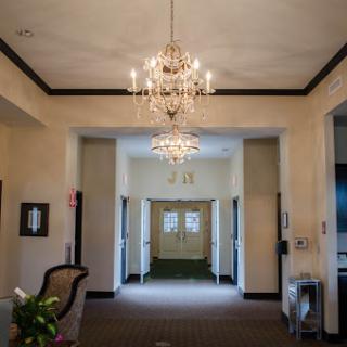 An elegant lobby featuring two chandeliers and a spacious hallway, creating an inviting atmosphere.