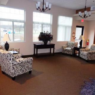 A cozy lounge area with several armchairs, a console table, and large windows letting in natural light.