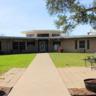 A suburban house with a grassy lawn and a pathway leading to the entrance.