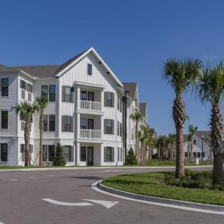 A modern apartment building surrounded by palm trees and well-maintained landscaping.
