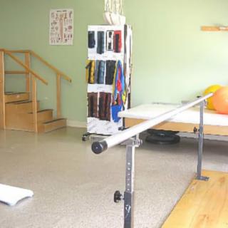 A physical therapy room equipped with parallel bars and various rehabilitation tools.