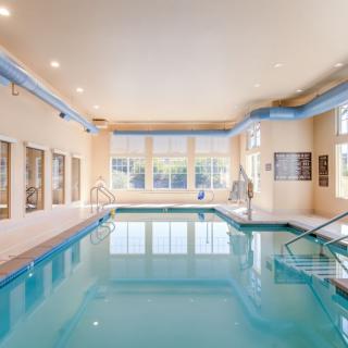A bright and modern indoor swimming pool area with large windows and a relaxing atmosphere.