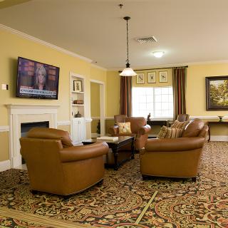 A cozy living room with comfortable sofas, a television mounted on the wall, and warm lighting.