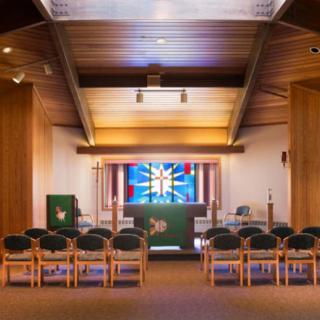 Interior of a chapel featuring an altar and stained glass window.