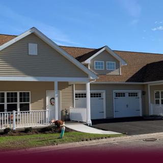 A suburban house with a double garage and porch, under a clear blue sky.