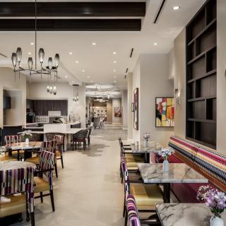 A modern and cozy restaurant dining area featuring colorful chairs and elegant chandeliers.
