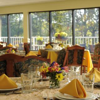 A beautifully set dining room with neatly arranged tables, complete with glassware, napkins, and floral centerpieces.