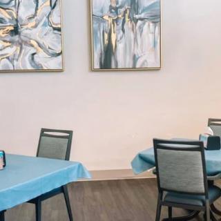 A modern dining area with blue tablecloths and abstract artwork on the walls.