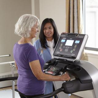 Senior woman receiving guidance from a trainer while using a treadmill.