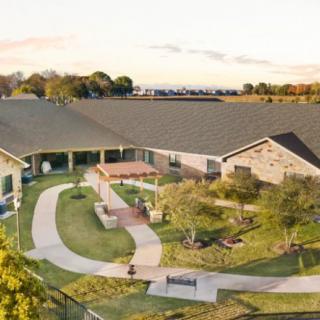 Aerial view of a residential building surrounded by a landscaped garden.